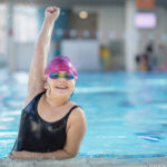 young and successful swimmers pose in swimming pool